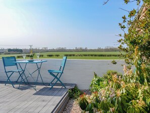An outdoor patio with a table and chairs, a bottle of champagne, and a glass.