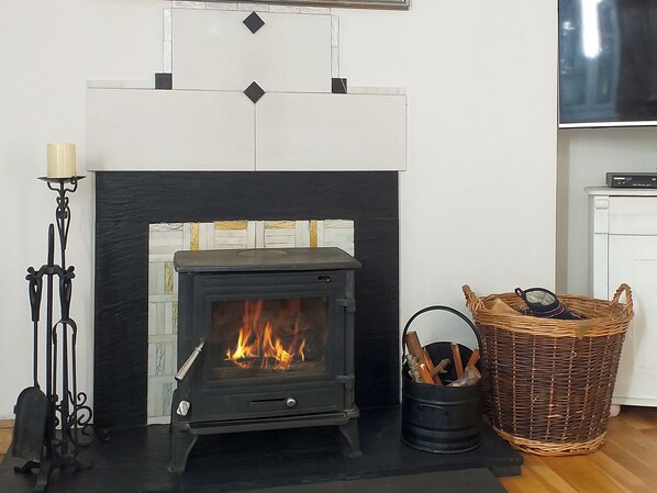A modern living room with a black fireplace, a decorative wall, a wicker basket, and a TV on a stand.