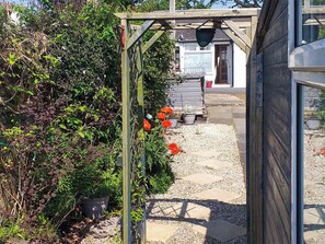 Un sendero de jardín con macetas y una estructura de pérgola de madera.