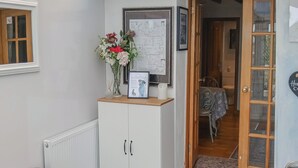 A hallway with a white cabinet, a bench, a door leading to a dining area, and a framed certificate on the wall.