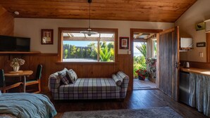 Una habitación acogedora con techo de madera, un sofá, un televisor, una mesa de comedor con sillas y vistas al exterior.