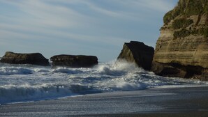 Paisaje costero con acantilados rocosos y olas rompiendo en la orilla.