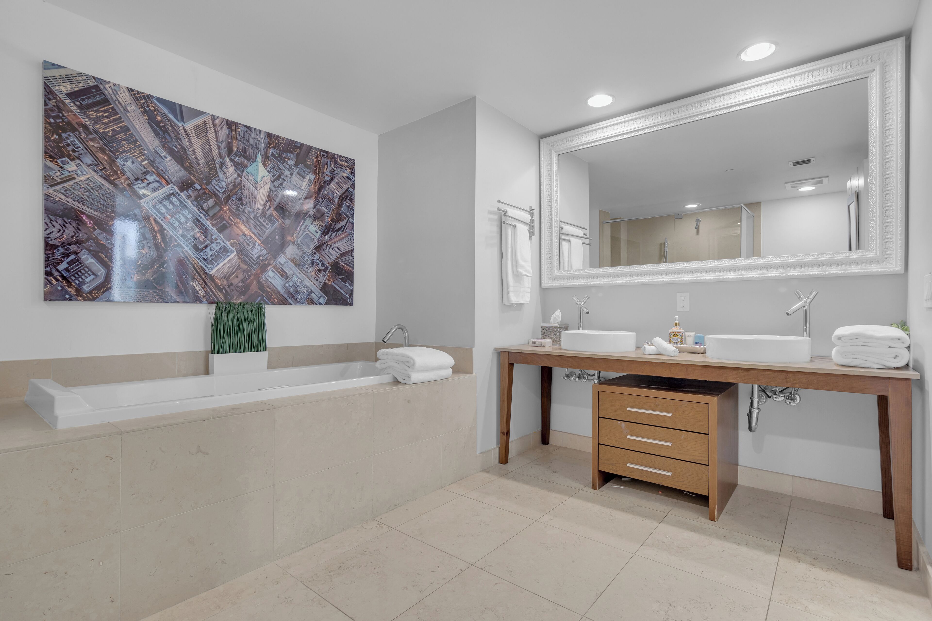 Une salle de bain moderne avec une grande baignoire, un meuble-lavabo en bois et un grand miroir.