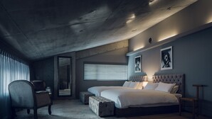 A bedroom with a large bed, a chair, a small table, and a window with blinds. - Node Hotel (Kyoto)