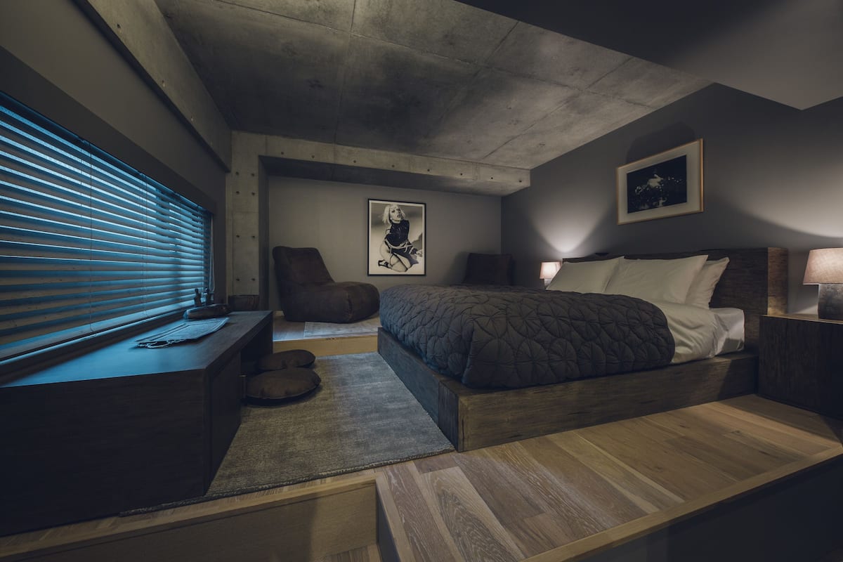 A modern bedroom with a bed, bedside tables, a desk, and a chair.