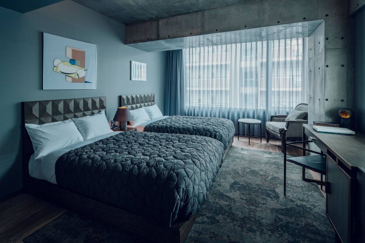 A hotel room with two beds, a desk, and a chair.