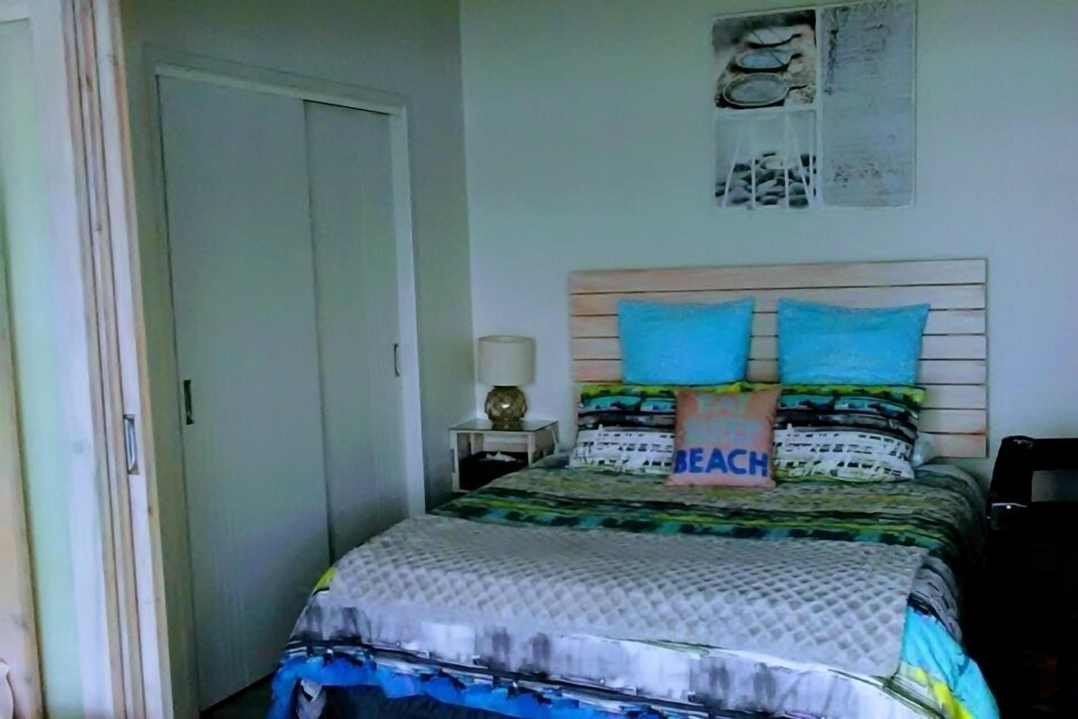 A bedroom with a bed, a nightstand, and a wall-mounted shelf.