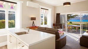 A modern kitchen with a large island, a dining area with a table and chairs, and a view of the ocean through large windows. - Lake Villa 3 Bedroom in Kingston (Kingston)