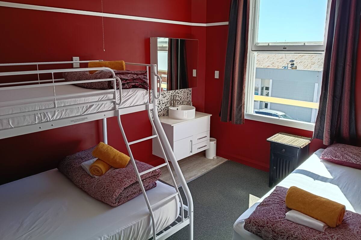 A bunk bed room with a window, a desk, and a mirror.