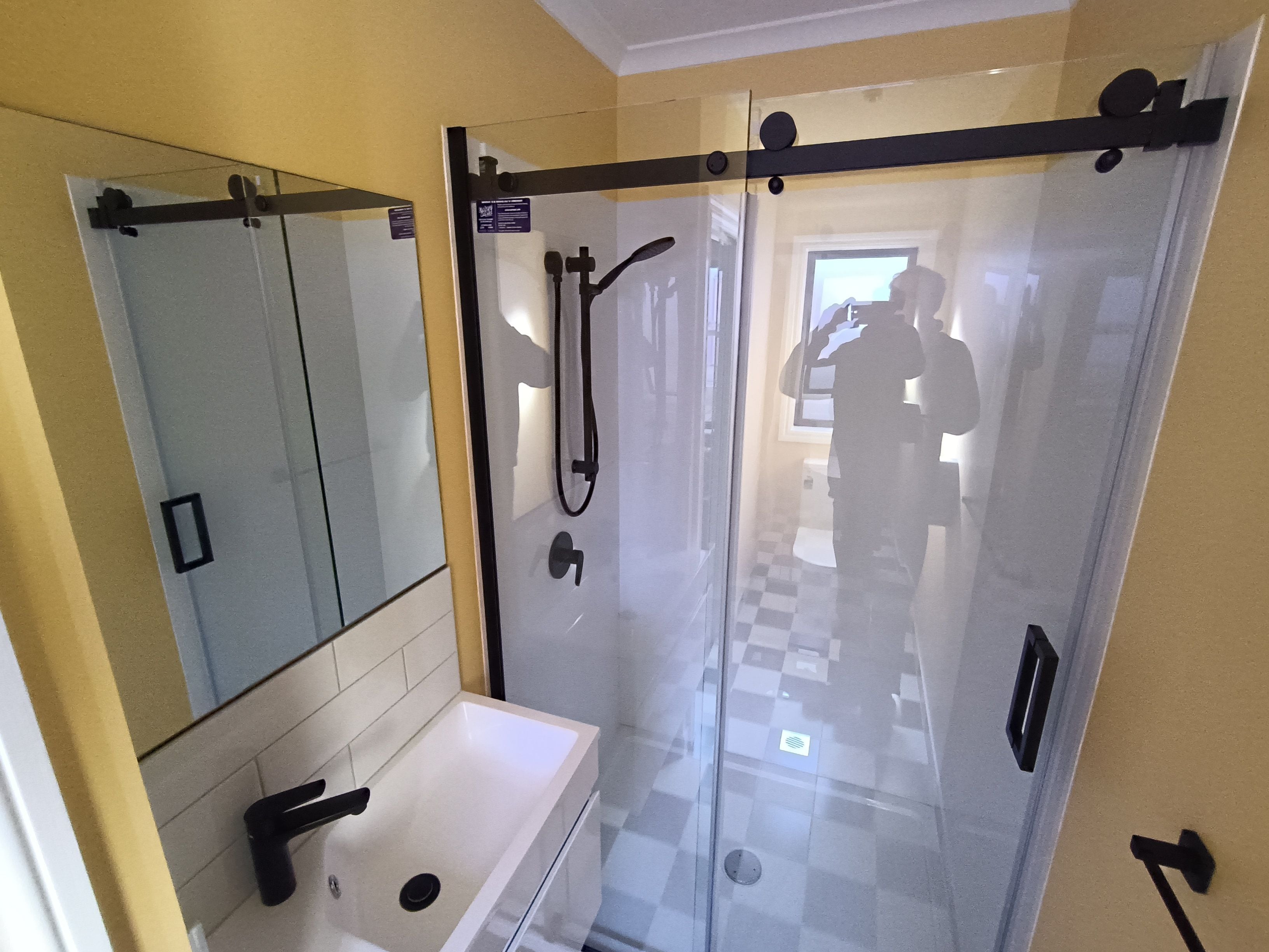 Un bagno con box doccia in vetro, lavandino e specchio.