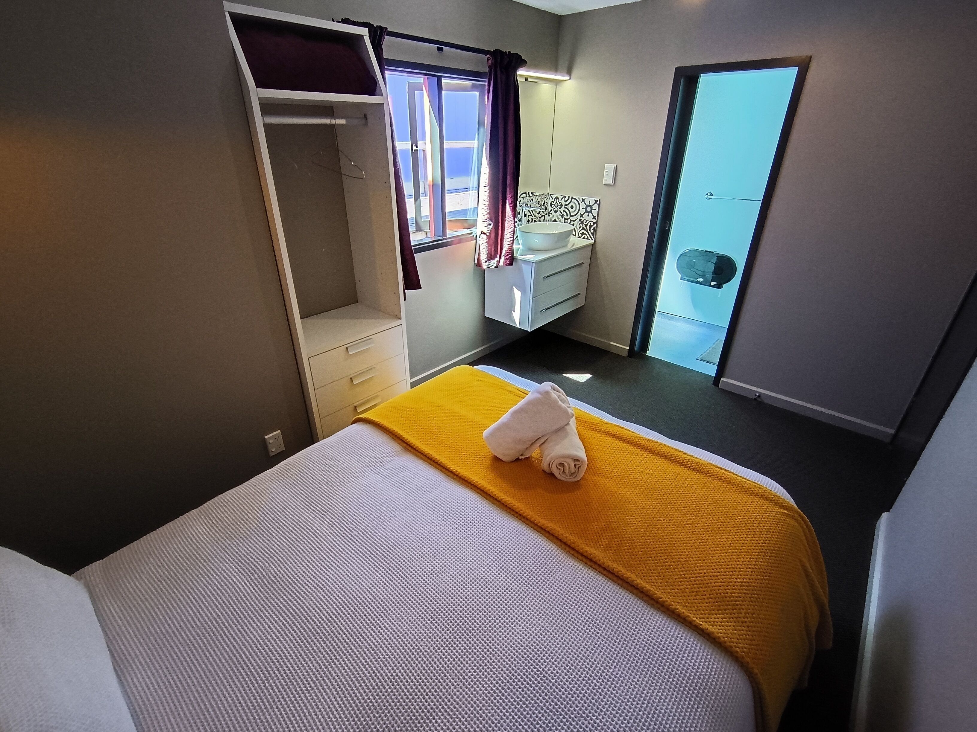 A hotel room with a bed, a bathroom, and a closet.