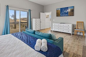 A bedroom with a bed, a sofa, a dresser, a chair, and a view of the outdoors. - Sandfiddler | Oceanfront | Dog Friendly, Private Pool, Hot Tub | Nags Head (Nags Head)