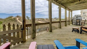 A wooden deck with picnic tables and benches, overlooking a beach and dunes. - Sandfiddler | Oceanfront | Dog Friendly, Private Pool, Hot Tub | Nags Head (Nags Head)