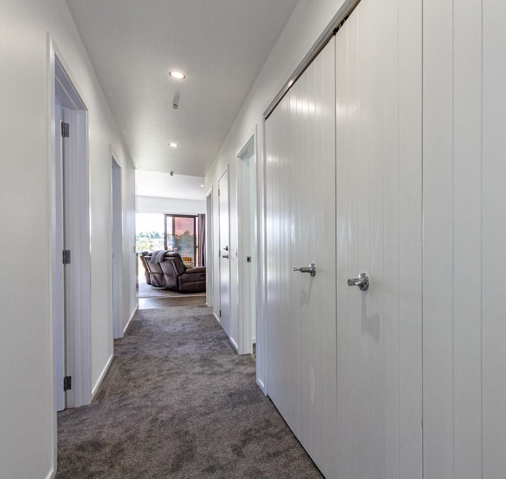 A hallway with carpeted flooring, white walls, and a sliding door on the right.
