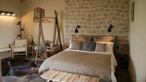 Un dormitorio acogedor con pared de piedra, cama de madera y una silla rústica.