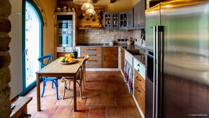 Una cocina con una mesa de madera, sillas, un refrigerador y una estufa.