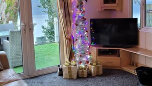 Un soggiorno con televisore, albero di Natale e camino.
