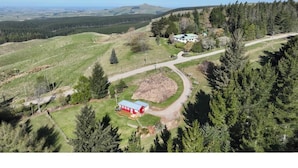 A rural landscape with a red building, a white structure, and a dirt path.
