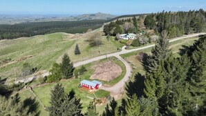A rural landscape with a red building, a white structure, and a dirt path. - Historic School in rural Oamaru with farm animals and outdoor baths (Oamaru)