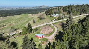 A rural landscape with a red building, a white structure, and a dirt path. - Historic School in rural Oamaru with farm animals and outdoor baths (Oamaru)