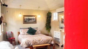 A cozy bedroom with a bed, a bench, a dresser, and a mirror.