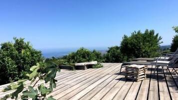 A wooden deck with lounge chairs and a view of the ocean.