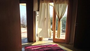 Ein Zimmer mit einer großen Glasschiebetür, die zu einem Außenbereich führt, einem gemusterten Teppich auf dem Boden und einem hölzernen Türrahmen.