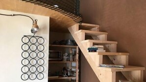 Eine kompakte Küche mit einer Holztreppe, die zu einem Erker führt, einer Hängeleuchte und einem Kühlschrank.