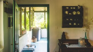 Une pièce avec une étagère en bois où sont posés de la vaisselle, une petite statue et un chandelier. Une fenêtre offre une vue sur la verdure à l’extérieur.