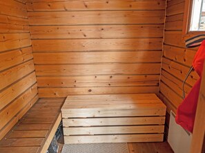 A sauna room with wooden walls and a bench.