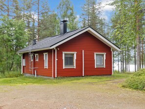A red wooden cabin with a sloped roof, a chimney, and two windows with shutters. - Lepokunnas by Interhome (Suomussalmi)