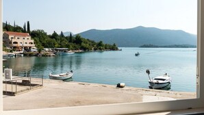 Vista sulla costa con un porto turistico, barche e un edificio con tetto rosso.