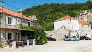 Un edificio in pietra con tetto in tegole rosse, una panchina all'esterno e diverse auto parcheggiate.