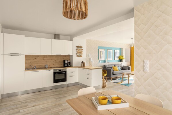 A modern kitchen with white cabinets, a wooden countertop, and a dining area with a wooden table and yellow chairs.