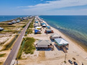 Vista aérea de una zona costera con casas de playa y una carretera que discurre paralela a la orilla.
