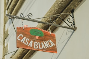 Un letrero de madera con el texto 'CASA BLANCA' colgado de un soporte metálico.