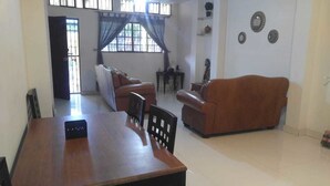 Uma sala de estar com uma mesa de jantar de madeira, dois sofás e um violão.