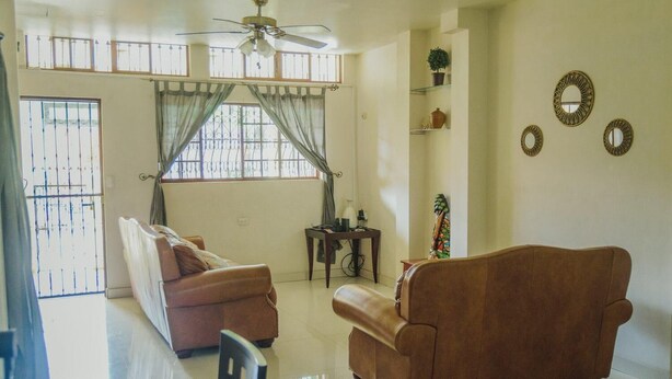 Uma sala de estar com dois sofás, um ventilador de teto e uma mesa de jantar.