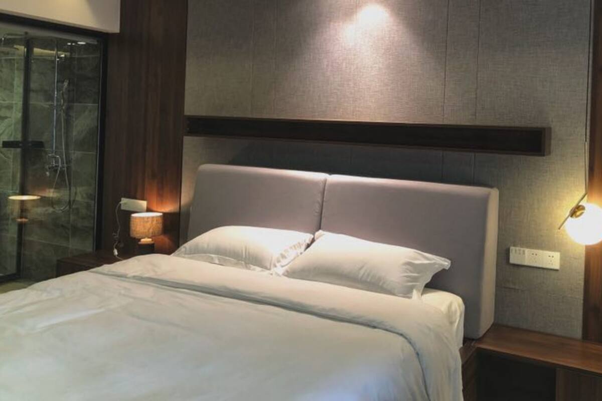 Une chambre d’hôtel moderne dotée d’un grand lit, d’une douche à parois de verre et d’un éclairage fixé au mur.
