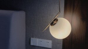 A modern room with a white bed, a textured grey wall, a wooden floor, and a minimalist pendant light fixture. - Wu Zhou City Ai Zhuke Shan Hai Apartment (Wuzhou)