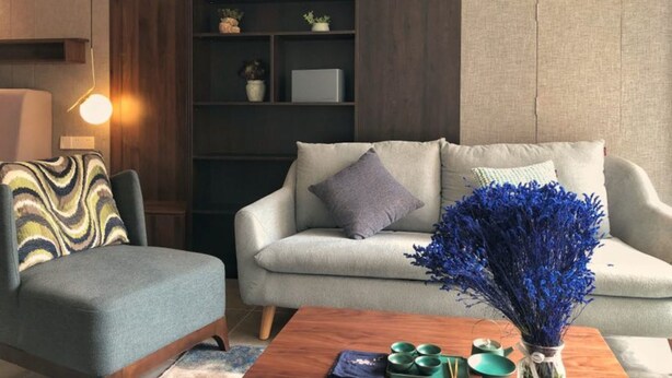 A modern living room with a grey sofa, a wooden coffee table, and a bookshelf. - Wu Zhou City Ai Zhuke Shan Hai Apartment (Wuzhou)