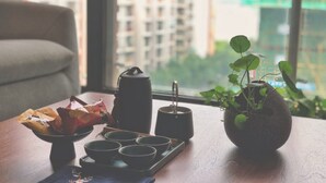 A table with a tray of teacups, a teapot, a bag of snacks, and a potted plant. - Wu Zhou City Ai Zhuke Shan Hai Apartment (Wuzhou)