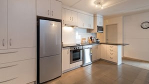 A modern kitchen with white cabinets, stainless steel appliances, and a black countertop.
