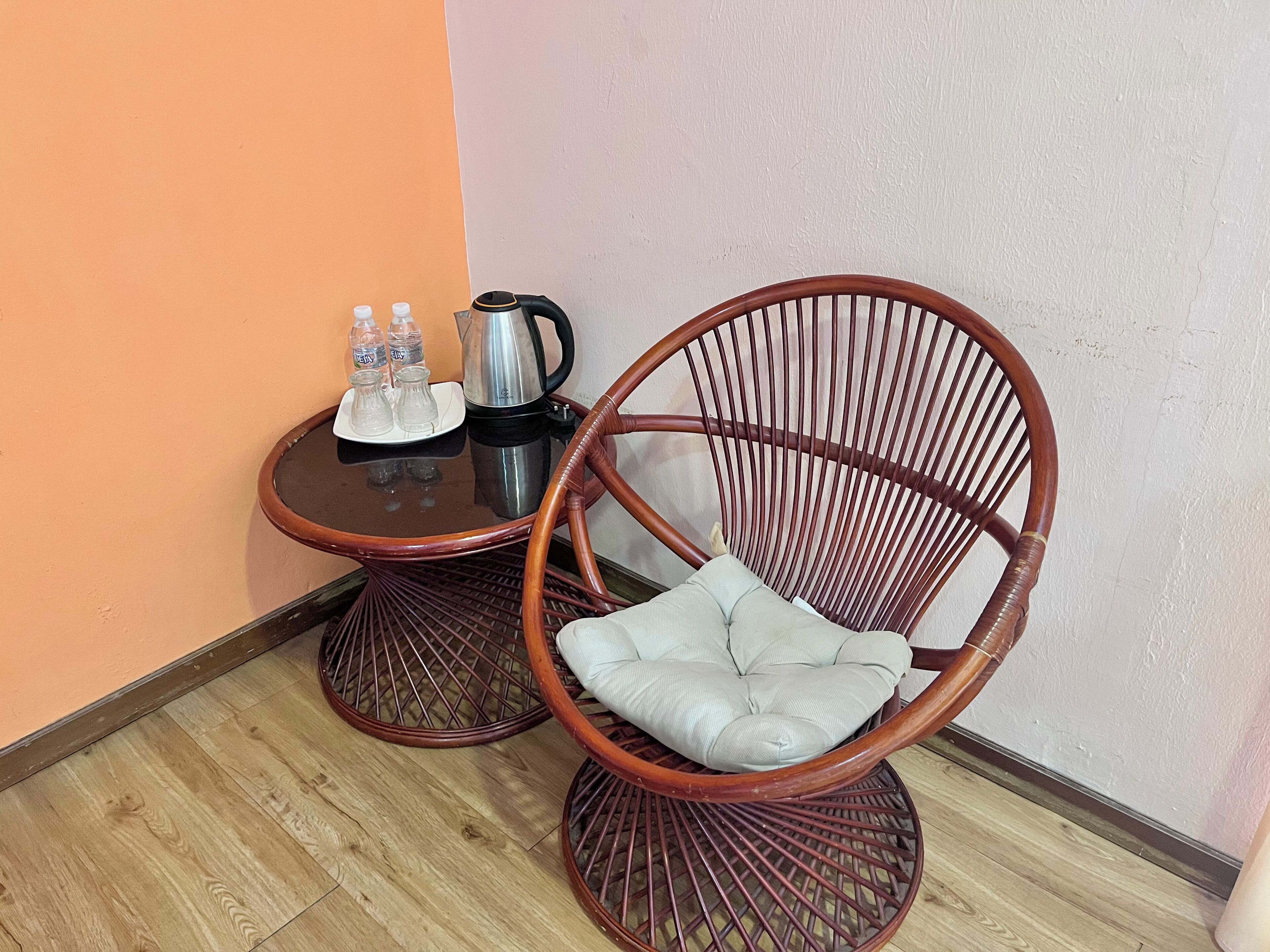 Une pièce d’angle avec une table ronde en bois, une chaise en osier et une petite table basse.