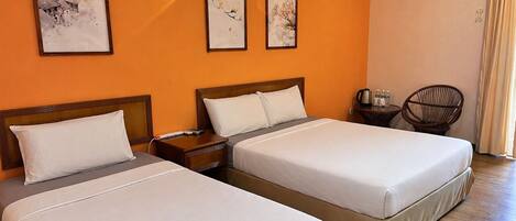 A hotel room with two beds, a nightstand, a chair, and artwork on the wall.