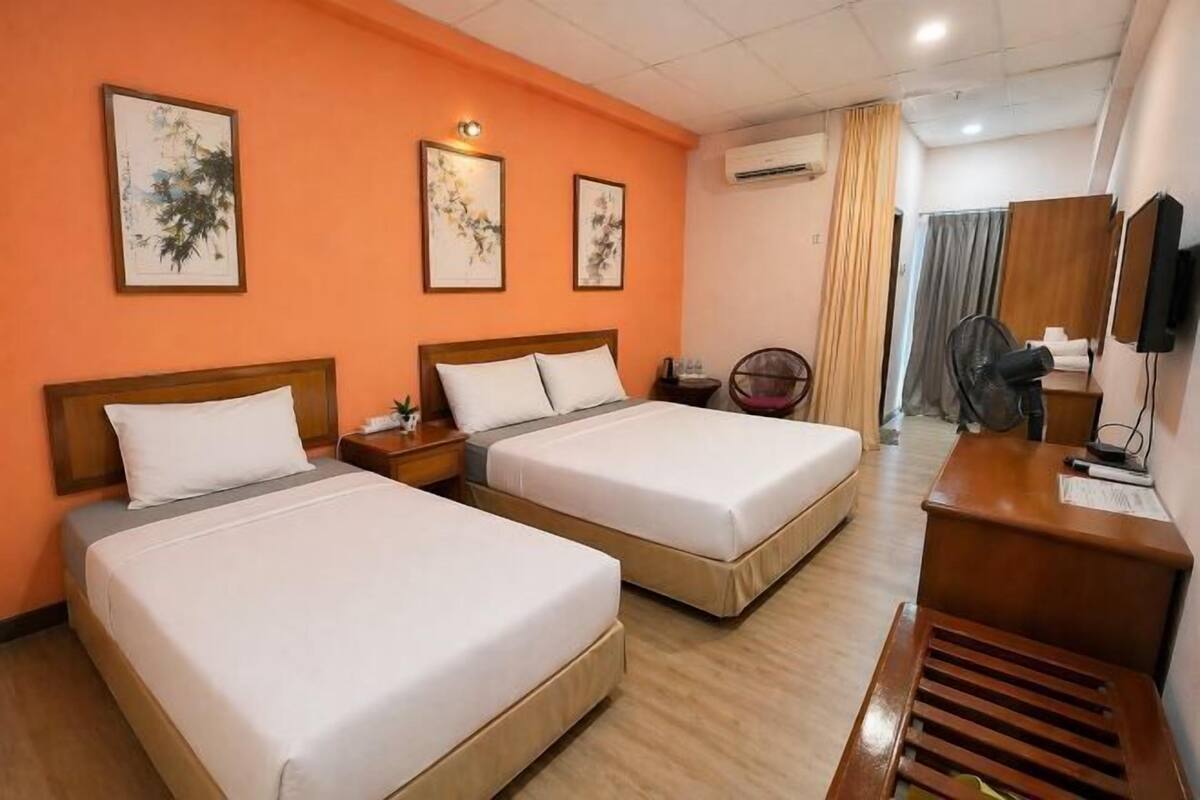 A hotel room with two beds, a desk, a chair, and artwork on the walls.