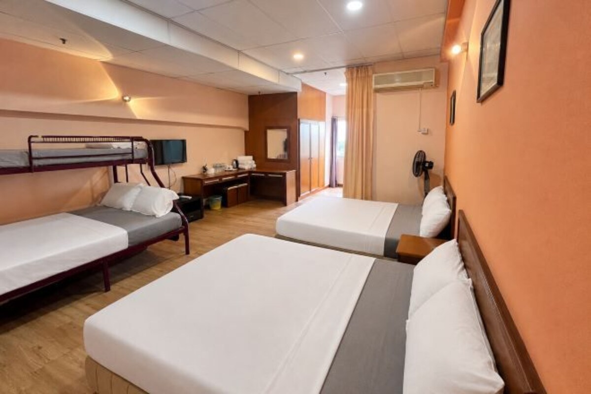 A hotel room with two single beds, a desk, a chair, a TV, and a window with curtains.