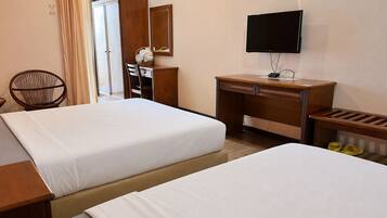 A hotel room with two beds, a desk, a chair, a television, and a mirror.