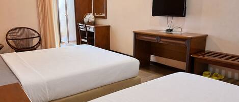 A hotel room with two beds, a desk, a chair, a television, and a mirror.