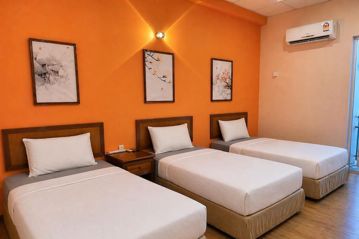 A hotel room with three single beds, an air conditioning unit, and framed artwork on the wall.